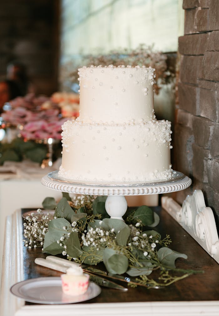 our-services-1 Beautiful two-tier white cake with delicate floral decorations, perfect for weddings and anniversaries.