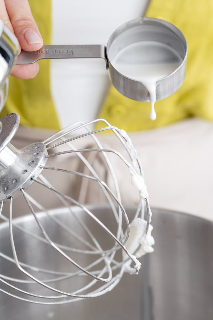 why-choose-us Crop unrecognizable female confectioner pouring melted sugar syrup into planetary mixer with whipped egg whites